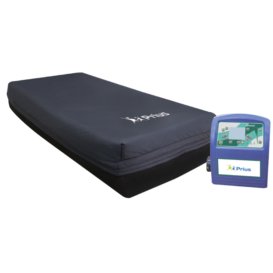 A rectangular anti-decubitus air mattress with a dark, smooth cover and the Prius logo features a digital control unit with a screen and buttons, designed for medical use as the Prius Duet LAL Alternating Mattress System, it provides pressure relief support.